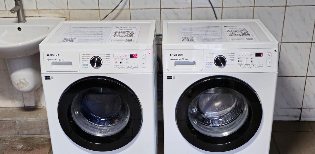 Дві пральні машини з наклейками QR-оплати NAGLYAD.WASH на реалізованому обʼєкті