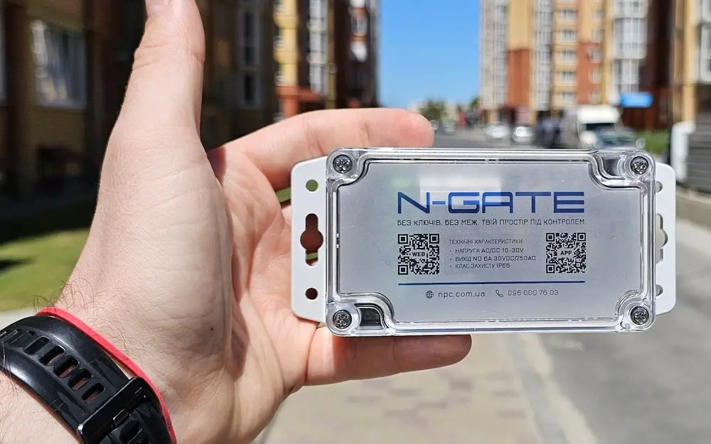 Контролер доступу N-GATE у руці на тлі житлового комплексу