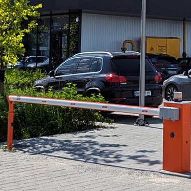 Шлагбаум на в’їзді до парковки гостьового будинку з припаркованими автомобілями